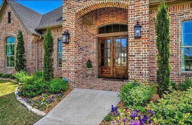 entrance to property featuring french doors, brick siding, and roof with shingles