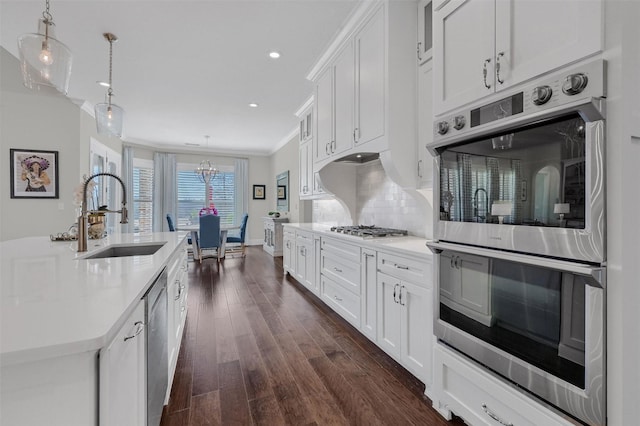 kitchen with dark wood finished floors, light countertops, decorative backsplash, stainless steel appliances, and a sink