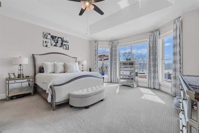 carpeted bedroom with baseboards, a raised ceiling, ceiling fan, and crown molding