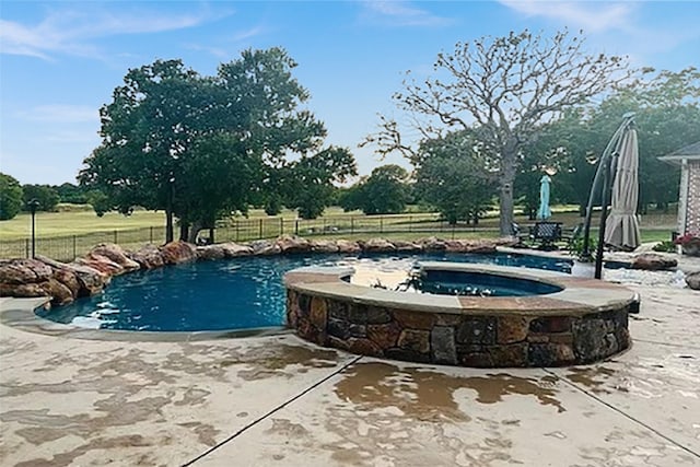 view of swimming pool featuring a pool with connected hot tub, a patio, and fence