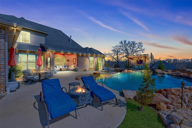 pool at dusk with a patio area, a pool with connected hot tub, and an outdoor fire pit