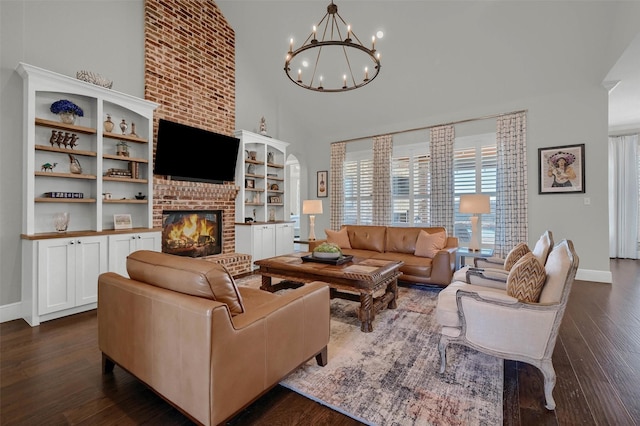 living room with a brick fireplace, baseboards, dark wood-type flooring, and a high ceiling