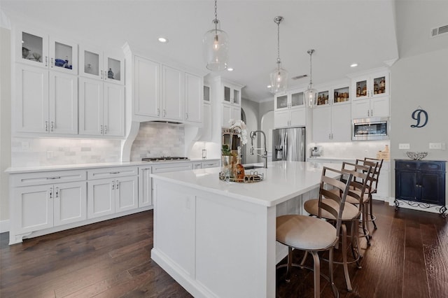 kitchen with a center island with sink, a sink, stainless steel appliances, light countertops, and dark wood-style flooring