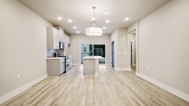 kitchen with light wood-style flooring, stainless steel appliances, visible vents, light countertops, and tasteful backsplash