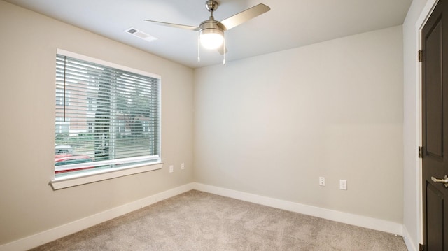 carpeted empty room featuring a ceiling fan, visible vents, and baseboards