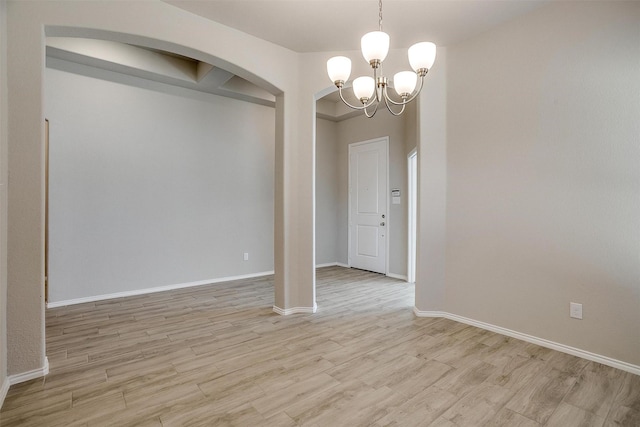 unfurnished dining area featuring baseboards, light wood-type flooring, and a notable chandelier