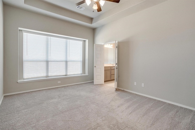 unfurnished bedroom with a raised ceiling, visible vents, light carpet, and baseboards