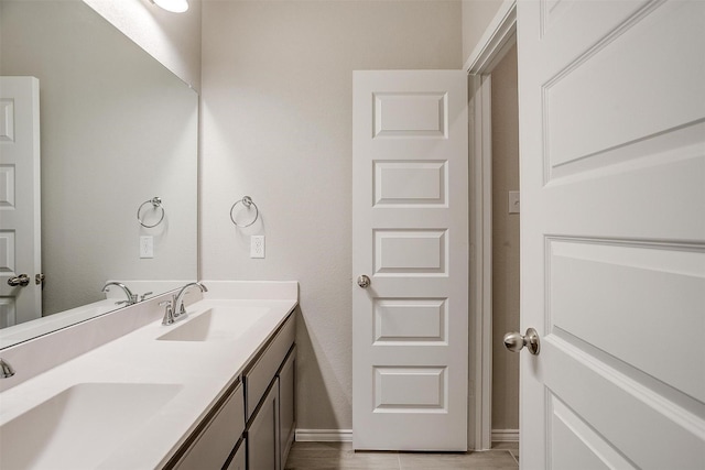 bathroom featuring double vanity, wood finished floors, a sink, and baseboards