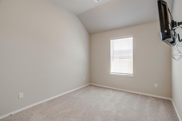 carpeted empty room featuring lofted ceiling, visible vents, and baseboards