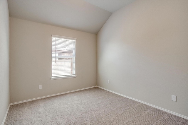 empty room featuring vaulted ceiling, carpet floors, and baseboards