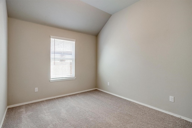 carpeted empty room with vaulted ceiling and baseboards