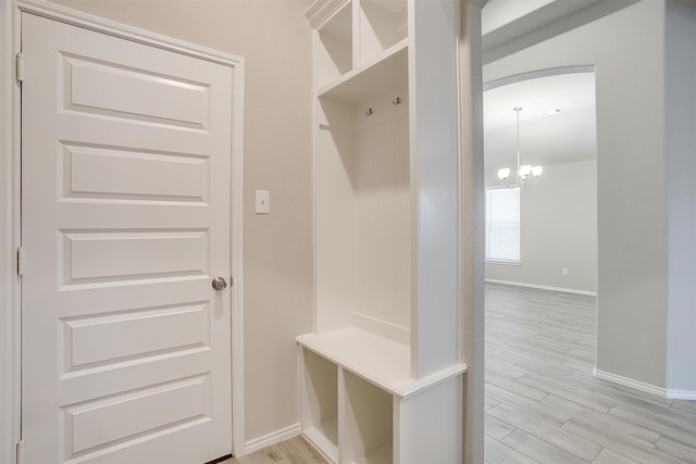 mudroom with baseboards, light wood-type flooring, and a notable chandelier