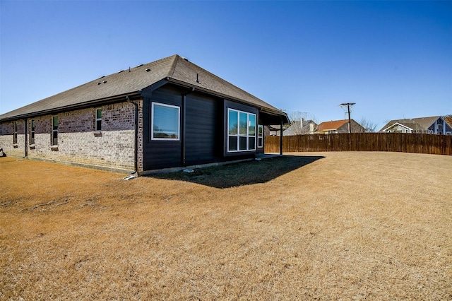 view of side of home with fence and brick siding