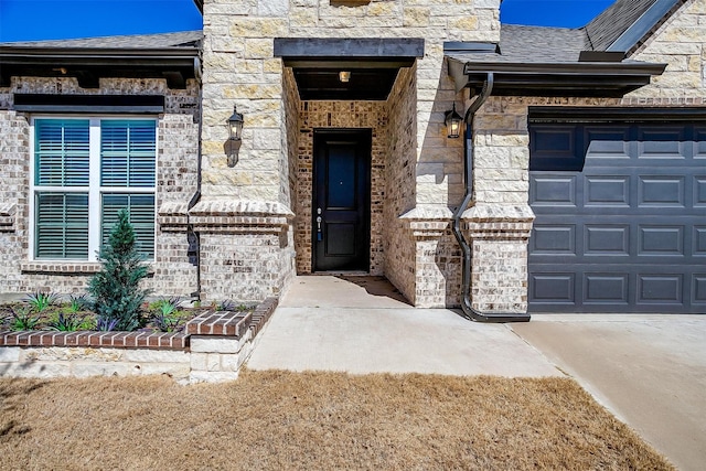 entrance to property with roof with shingles, brick siding, an attached garage, stone siding, and driveway