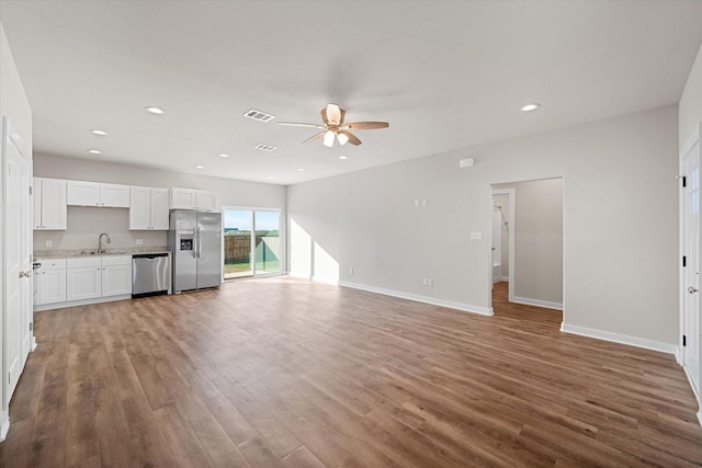 unfurnished living room featuring recessed lighting, ceiling fan, a sink, and wood finished floors