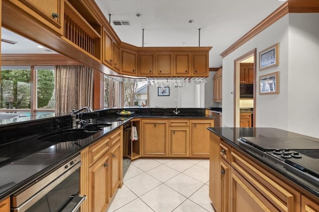 kitchen featuring light tile patterned floors, a sink, visible vents, dark stone counters, and black appliances