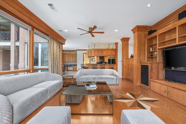 living room with built in shelves, recessed lighting, visible vents, light wood-style flooring, and a ceiling fan