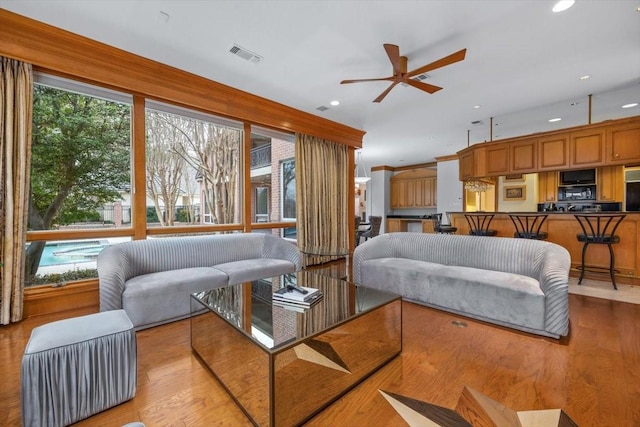 living room with a wealth of natural light, visible vents, light wood-style flooring, and recessed lighting