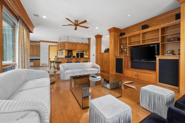 living area with ornamental molding, light wood-type flooring, ornate columns, and recessed lighting