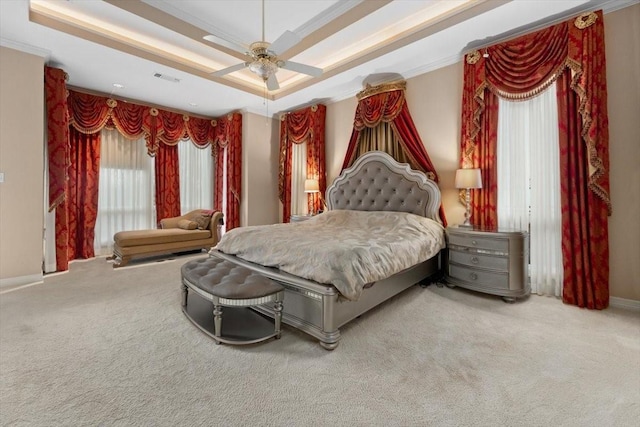 carpeted bedroom featuring visible vents, a raised ceiling, baseboards, ceiling fan, and ornamental molding