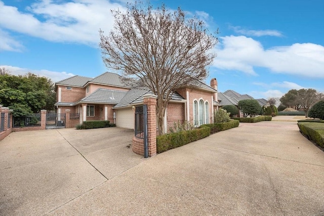 view of front facade with an attached garage, brick siding, fence, concrete driveway, and a gate