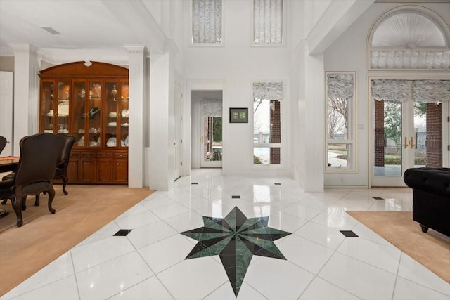 foyer entrance with french doors, a high ceiling, tile patterned flooring, and decorative columns