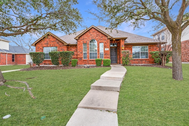 ranch-style house with roof with shingles, a front yard, and brick siding