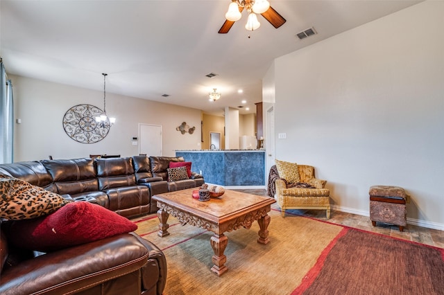 living area featuring ceiling fan with notable chandelier, baseboards, and visible vents