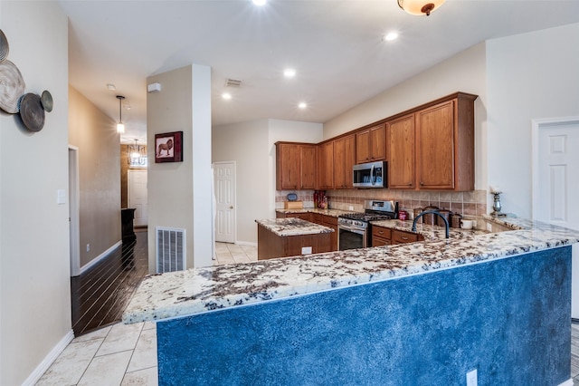 kitchen with stainless steel appliances, visible vents, backsplash, and light stone countertops