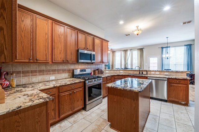 kitchen with visible vents, appliances with stainless steel finishes, brown cabinets, a peninsula, and a sink