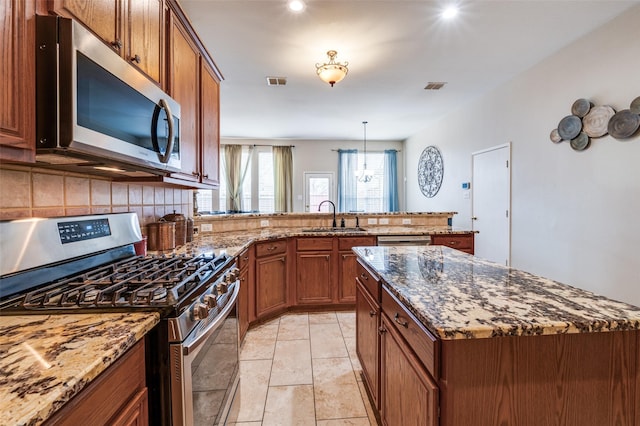 kitchen featuring stainless steel appliances, visible vents, backsplash, brown cabinetry, and a sink