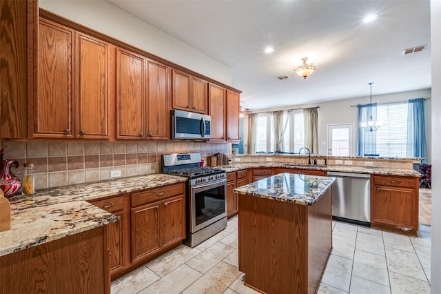kitchen with a peninsula, visible vents, brown cabinets, appliances with stainless steel finishes, and a sink