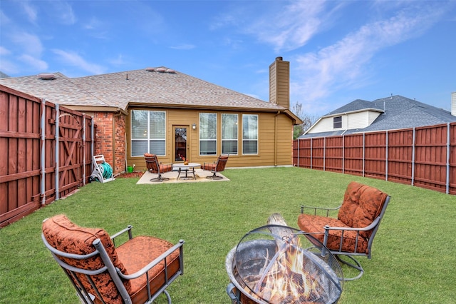 rear view of house featuring brick siding, a chimney, a patio area, a fenced backyard, and a fire pit