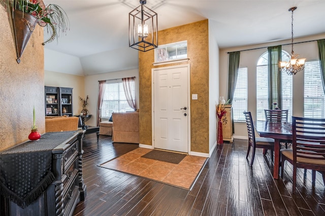 entryway featuring a chandelier, baseboards, vaulted ceiling, and wood finished floors