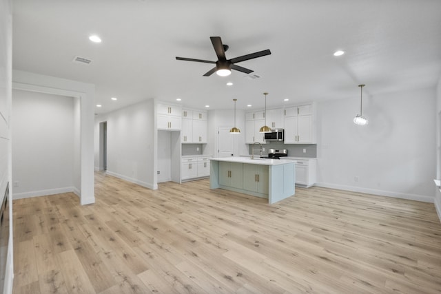 kitchen with stainless steel appliances, light countertops, white cabinets, and light wood-style flooring