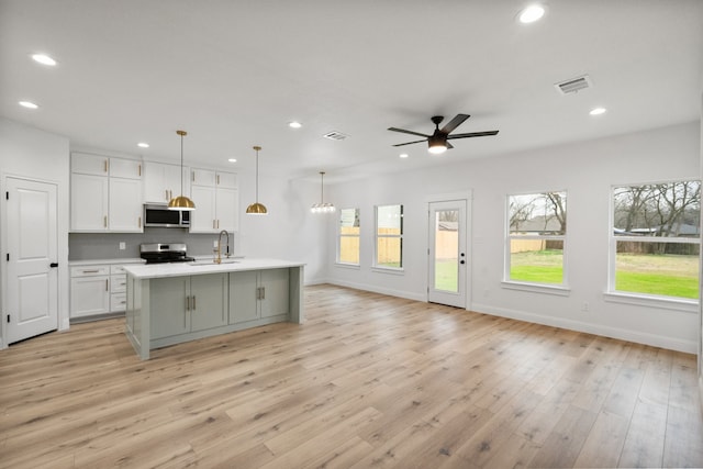 kitchen with recessed lighting, stainless steel appliances, white cabinets, open floor plan, and light countertops