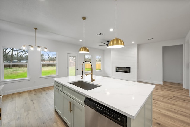 kitchen featuring a large fireplace, stainless steel dishwasher, light wood-type flooring, and a sink