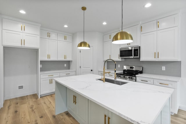 kitchen featuring a sink, white cabinetry, appliances with stainless steel finishes, light wood finished floors, and tasteful backsplash