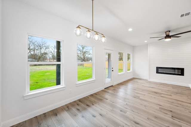 interior space with a large fireplace, baseboards, visible vents, and wood finished floors