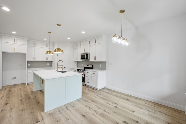 kitchen featuring appliances with stainless steel finishes, white cabinets, light countertops, and a sink