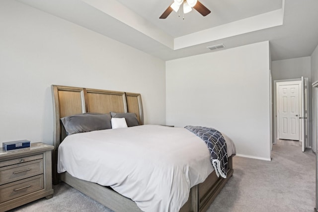 bedroom with baseboards, a raised ceiling, visible vents, and light colored carpet