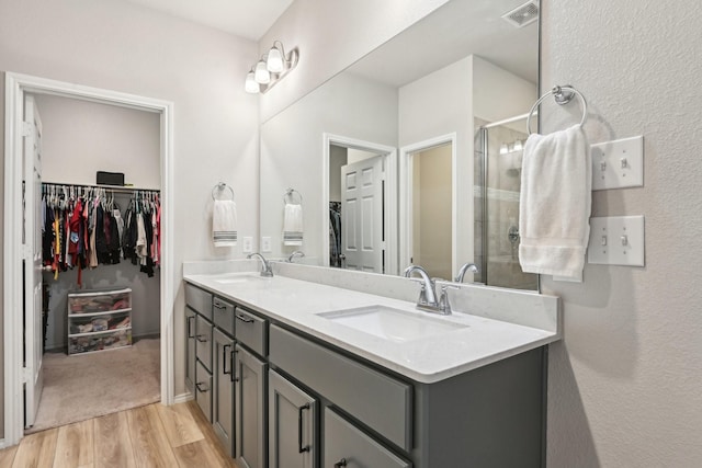 bathroom with wood finished floors, a sink, visible vents, and a walk in closet