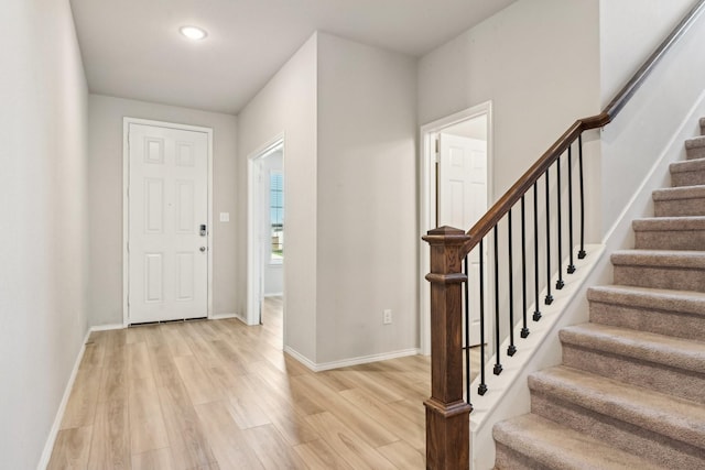 entryway with baseboards, recessed lighting, stairs, and light wood-style floors