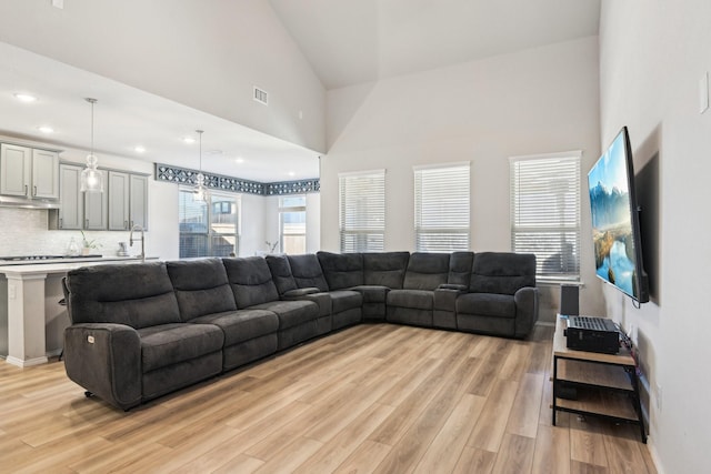 living room with high vaulted ceiling, recessed lighting, visible vents, baseboards, and light wood finished floors