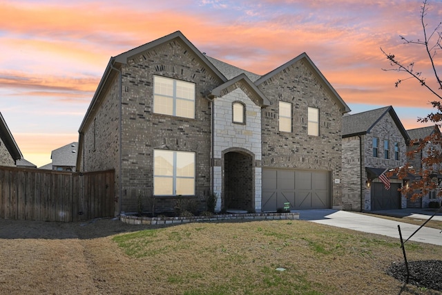 french country inspired facade with a garage, driveway, fence, a yard, and brick siding