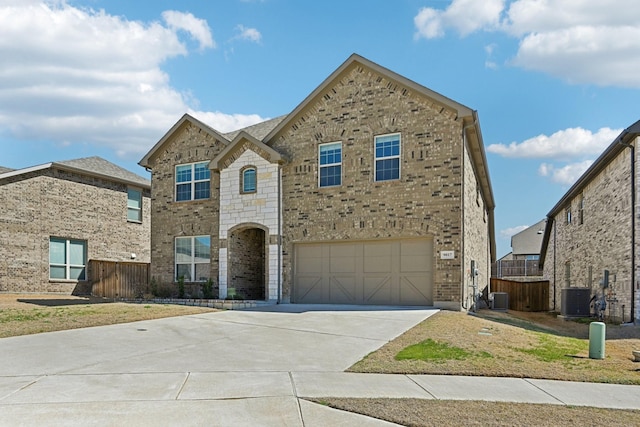 view of front facade with concrete driveway, brick siding, cooling unit, and fence