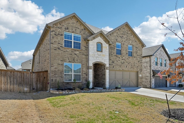 view of front of property with brick siding, an attached garage, a front yard, fence, and driveway