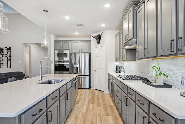 kitchen with stainless steel appliances, under cabinet range hood, and gray cabinetry