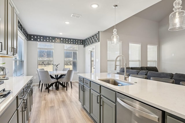 kitchen with a sink, light wood-style floors, light countertops, stainless steel dishwasher, and gray cabinets