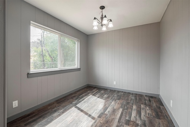 unfurnished room featuring a notable chandelier, baseboards, and wood finished floors